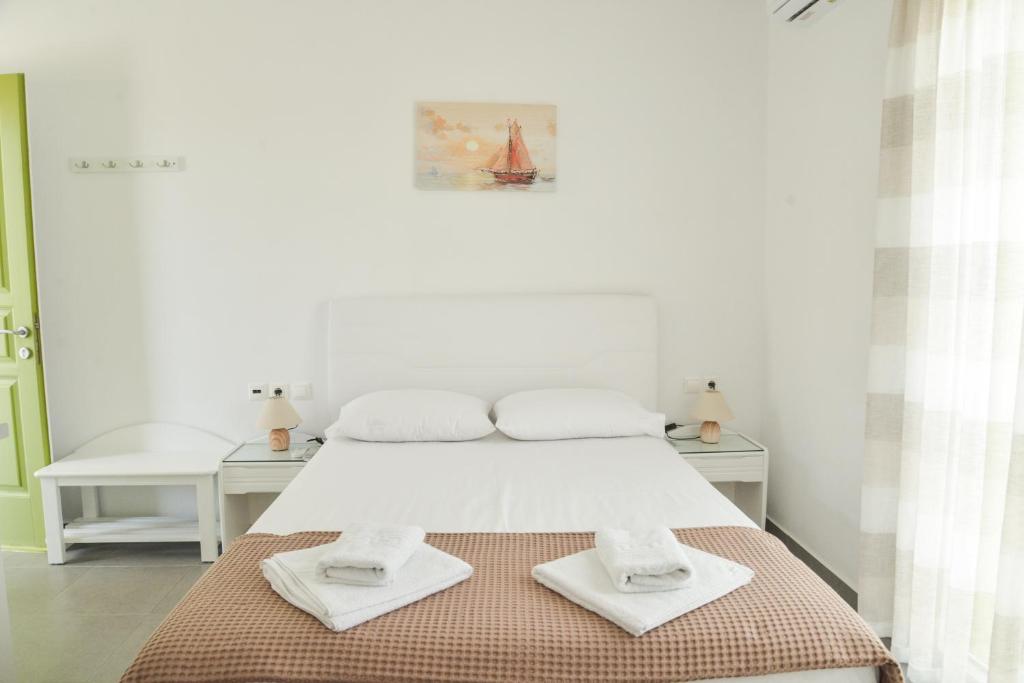 阿达玛斯Zeras Apartments的白色卧室,配有带毛巾的床