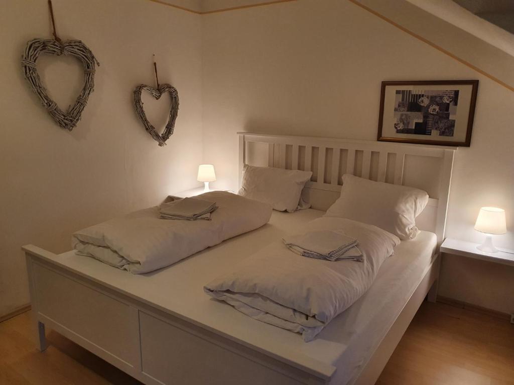 科隆CityPark Aparthotel的一张白色的床,墙上有两个枕头和两个心