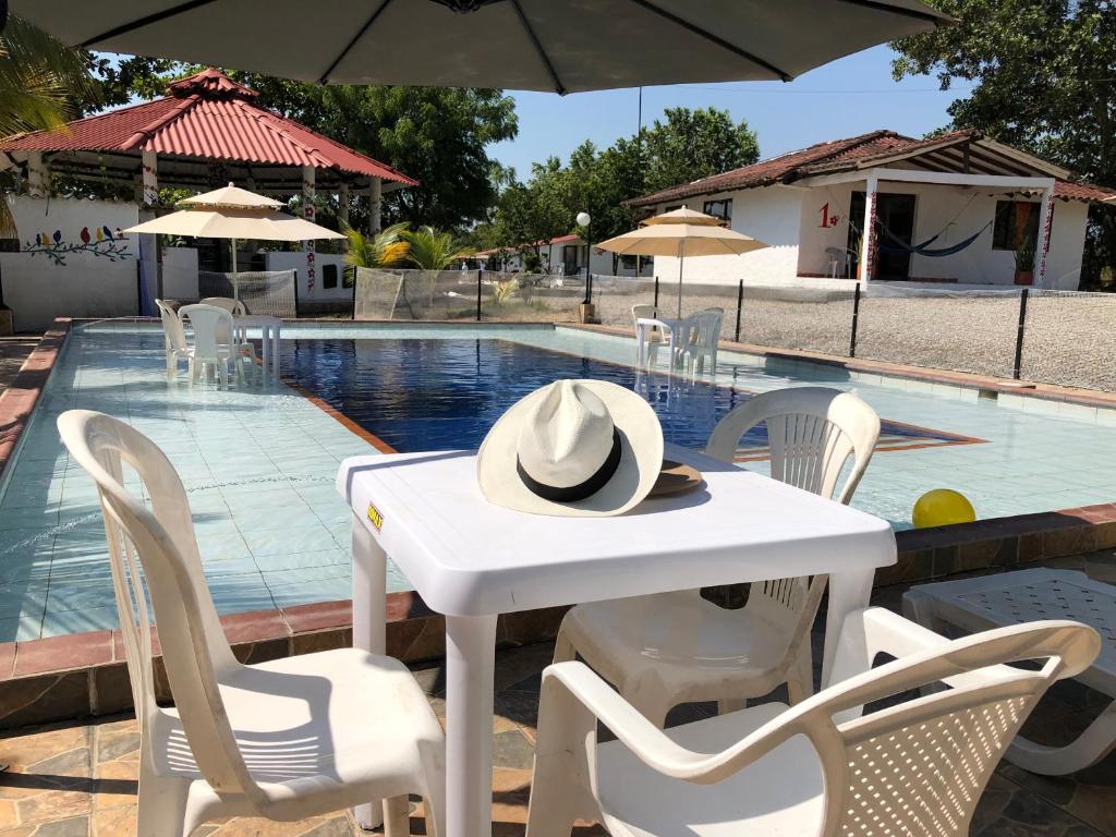 比亚维森西奥Cabañas Campestres en Villavicencio的一张带帽子的白色桌子,旁边是游泳池
