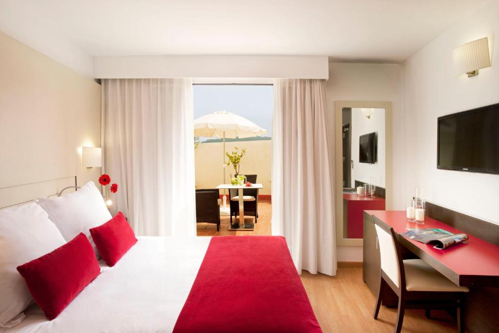巴塞罗那格拉维纳集团酒店的酒店客房配有一张床、一张书桌和一把遮阳伞。