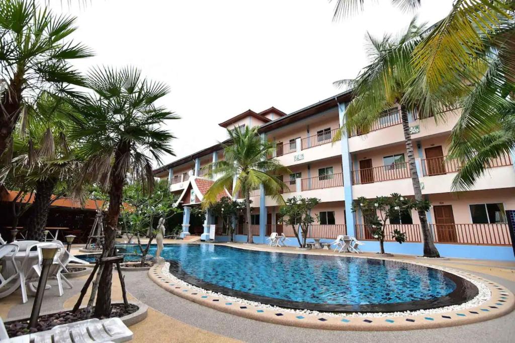 农布Ampan Resort & Apartment的棕榈树酒店前的游泳池