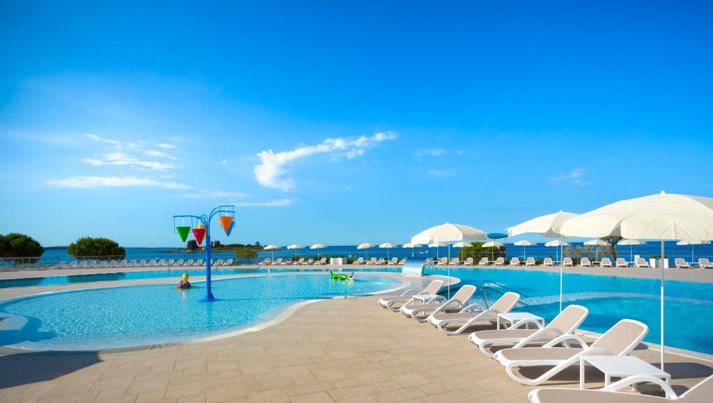 罗维尼Maistra Select Villas Rubin Resort的一个带椅子和遮阳伞的游泳池