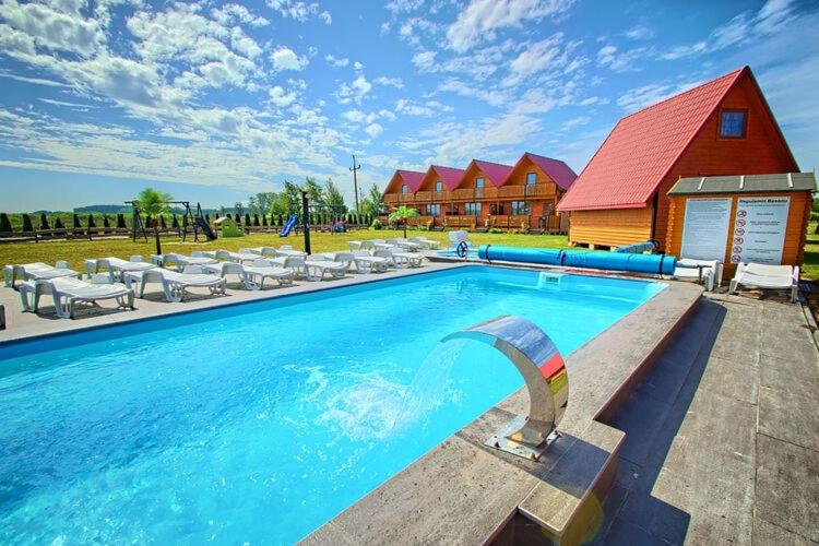 雅罗斯瓦维茨Holiday resort, Jaroslawiec的一座带椅子的大型游泳池和一座红色的建筑