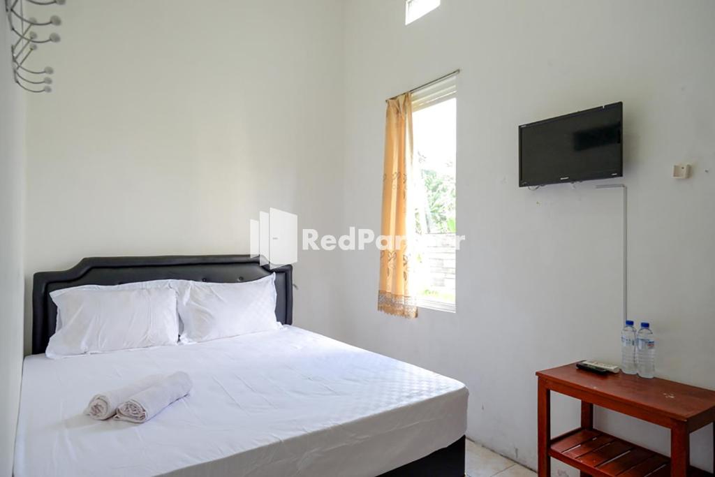 三宝垄Pringgondani Guest House At Pandanaran Hills Semarang的一间卧室配有一张带白色床单的床和电视。