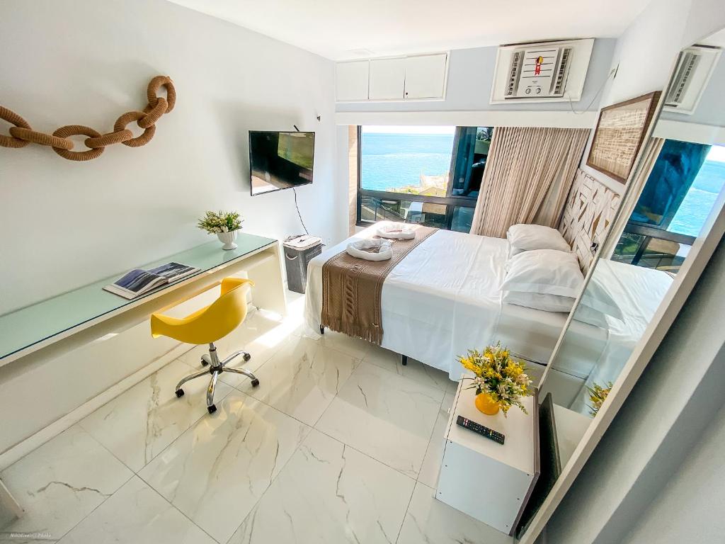 萨尔瓦多Ondina Apart Hotel Salvador的一间卧室配有一张床、一张书桌和一个窗户。