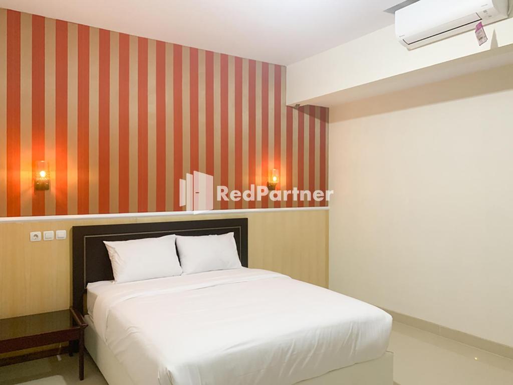 班图尔RedDoorz Syariah At Hotel Nuri Indah Dongkelan Yogyakarta的卧室配有白色的床和红色条纹墙