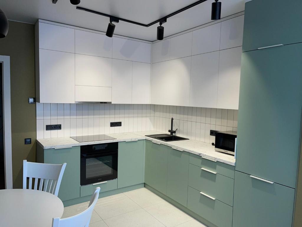 罗夫诺PRESTIGE-CENTER的厨房配有白色橱柜和桌椅