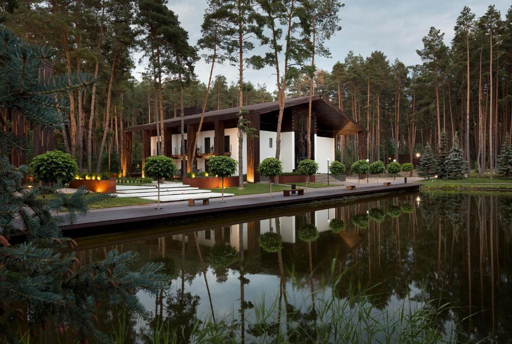 Sosnovka沃霍利休闲公园酒店的池塘旁树林中的房屋