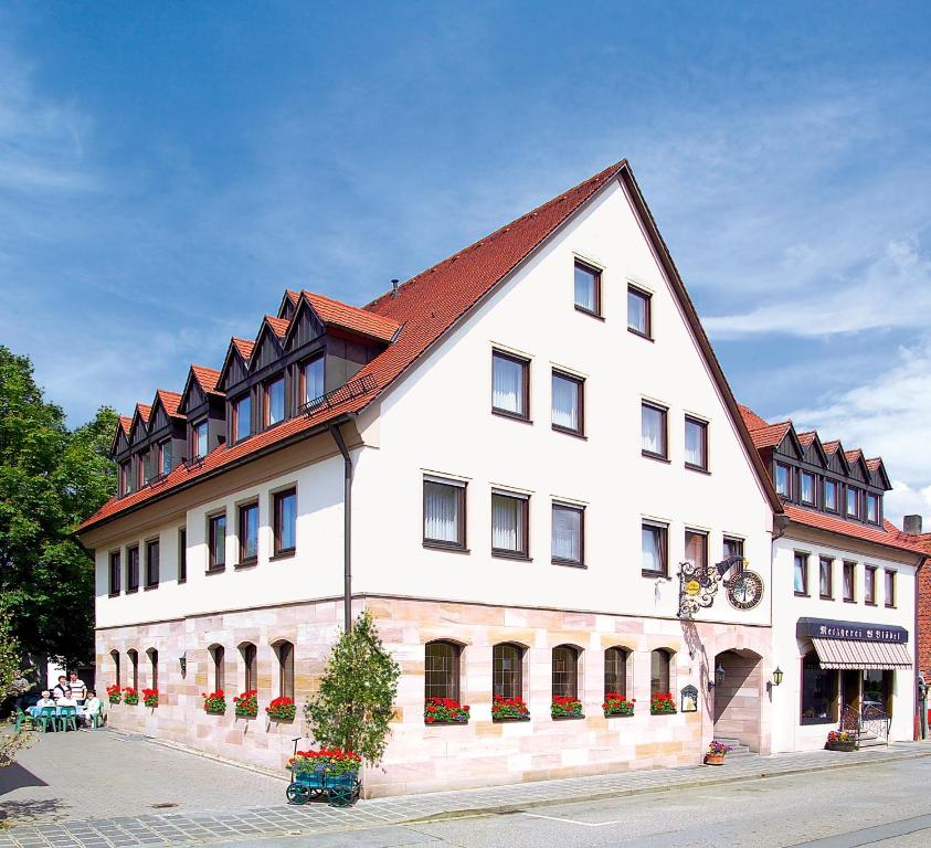 纽伦堡BLÖDEL Gasthof Grüner Baum的一座白色的大建筑,有红色的屋顶