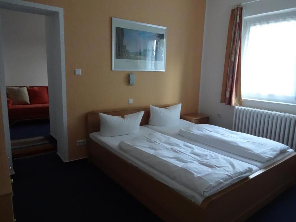 柏林Hotel Süden的一间卧室配有一张带白色床单的床和一扇窗户。