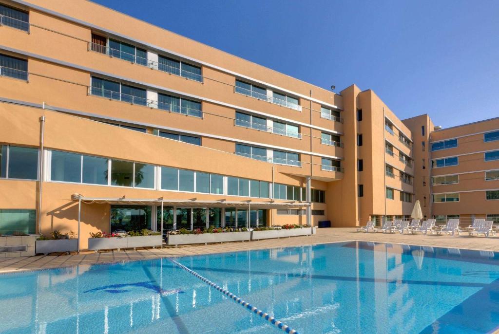 莱萨·达·帕尔梅拉TRYP by Wyndham Porto Expo Hotel的大楼前设有游泳池的酒店