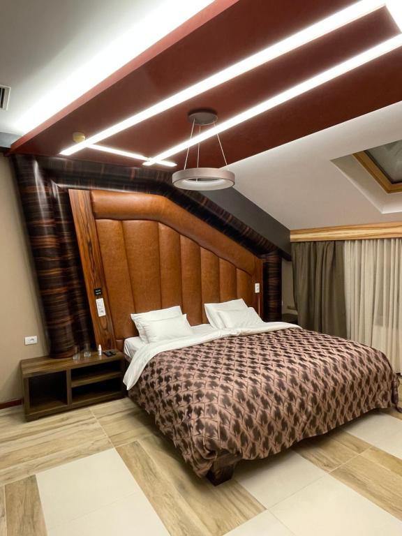 洛兹尼察Hotel Havana Loznica的卧室里有一张带木质床头板的大床