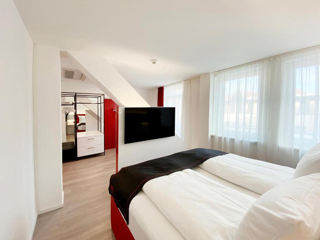黑尔斯布鲁克DORMERO Hotel Hersbruck的白色卧室设有一张大床和一台平面电视。