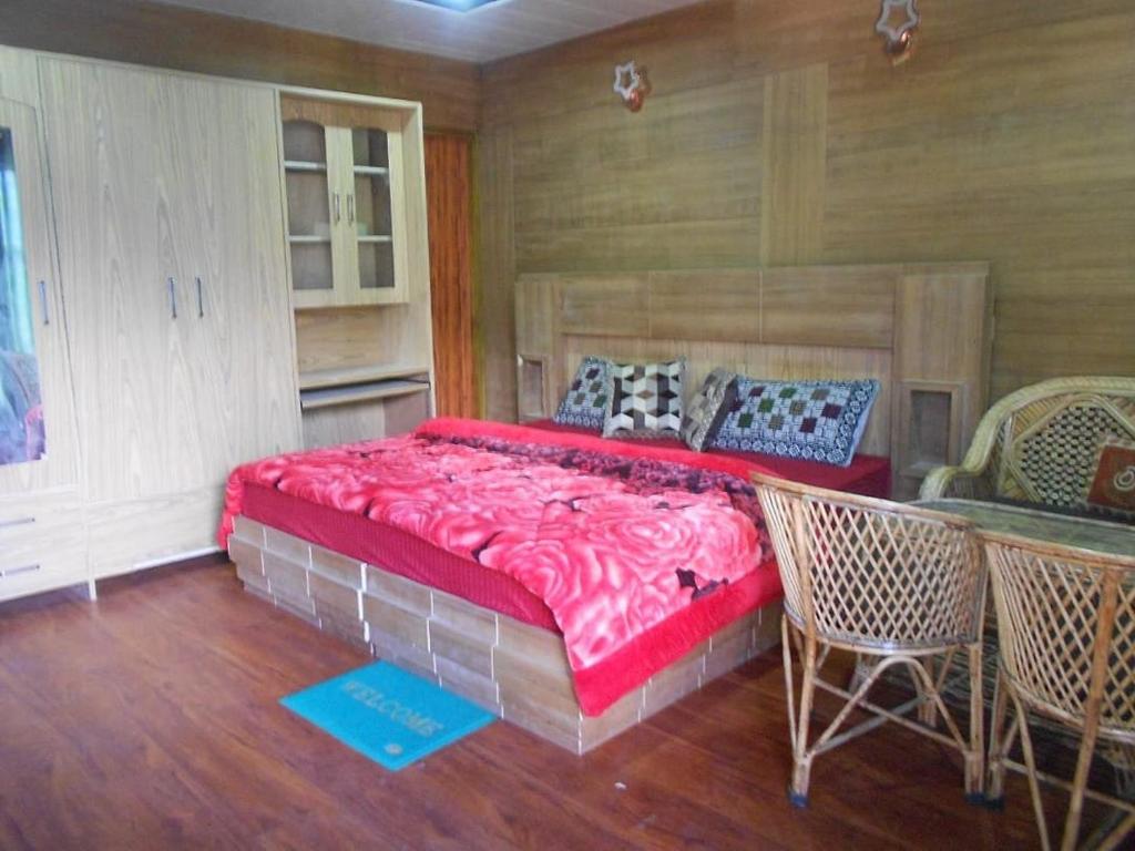 乔斯希马特Nandan Kanan Auli Resort的一间卧室配有一张大床和一张桌子及椅子