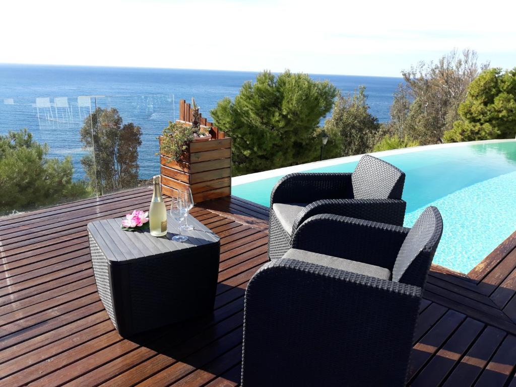 萨各夫雷纳Villa Luxury Paradise Suites的游泳池旁的甲板上配有椅子和桌子