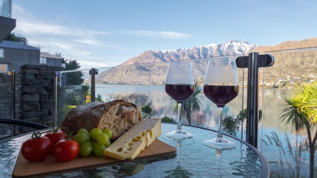 皇后镇Alpine Lakeside Studio的一张桌子,上面放着两杯葡萄酒和一盘食物