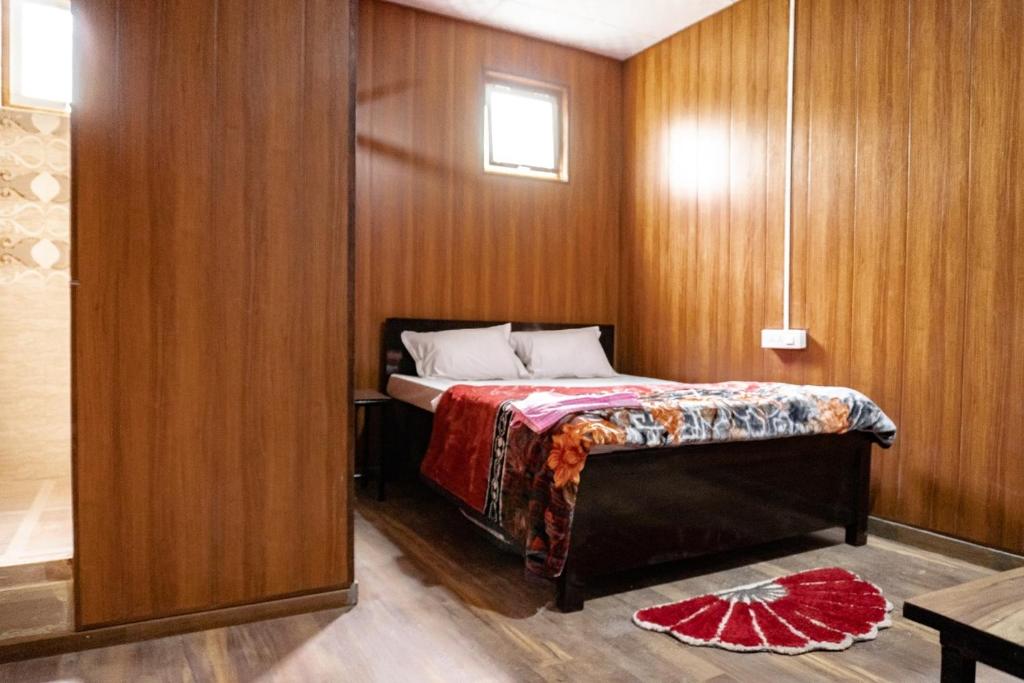 阿尔莫拉Mehra Cottage的木镶板客房内的一间卧室配有一张床