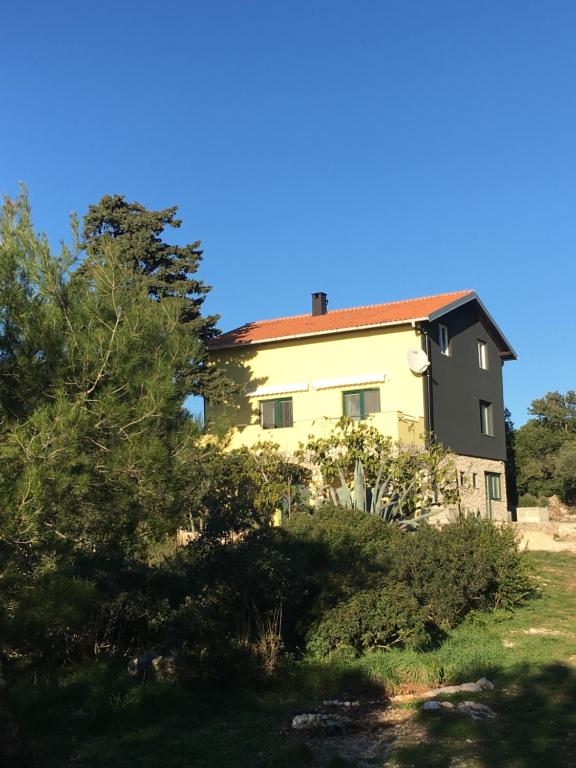 锡尔巴岛APARTMENT ŽUŽI Otok Silba Hrvatska的黄色的房屋,有红色的屋顶