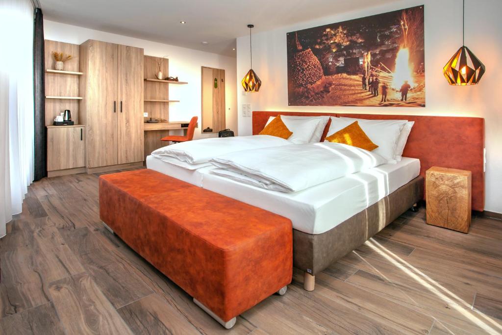 阿尔滕斯泰希Rose Bistro & Gästezimmer的一间卧室配有一张带橙色搁脚凳的大床