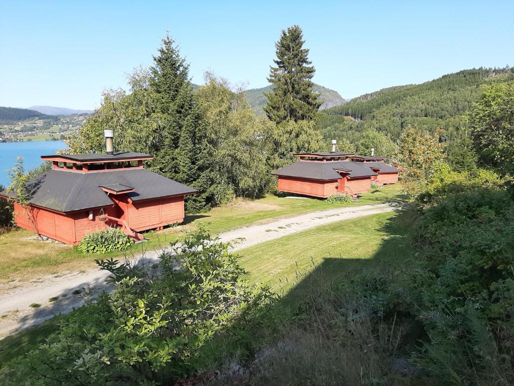 LusterKvamshaugen hytter的湖畔山丘上的2间红色小屋
