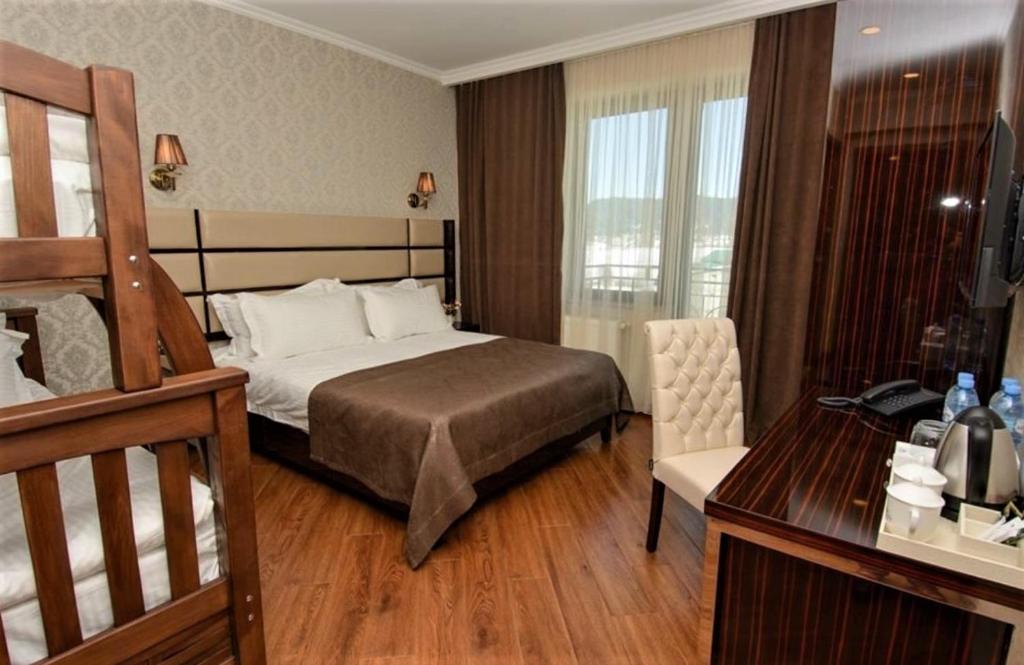 巴库里阿尼Hotel King David Bakuriani的酒店客房带一张床铺、一张书桌和一间卧室