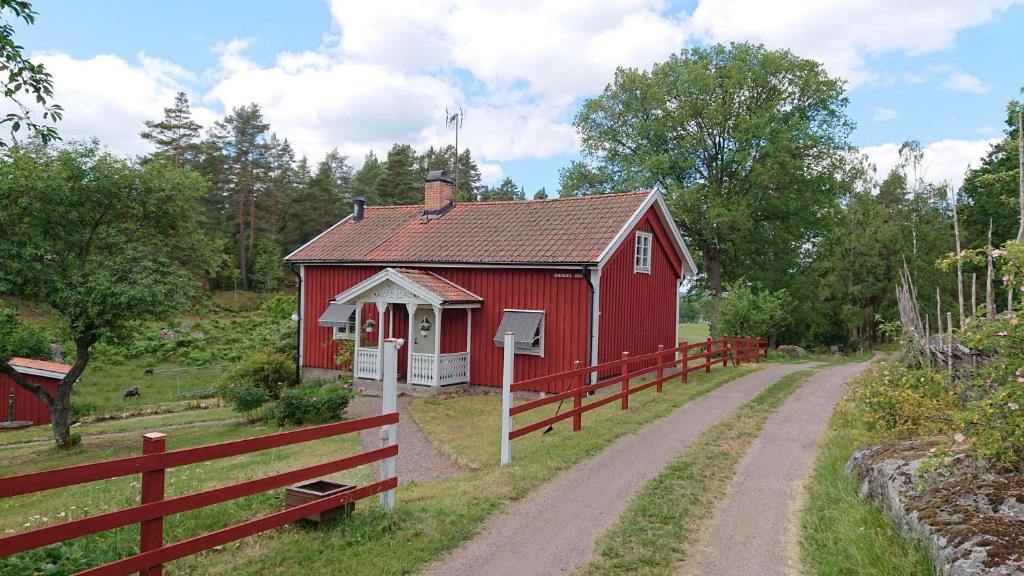 利姆福萨Året runt i väldigt härlig natur Bo på lantgård的泥路旁的红色谷仓,有栅栏