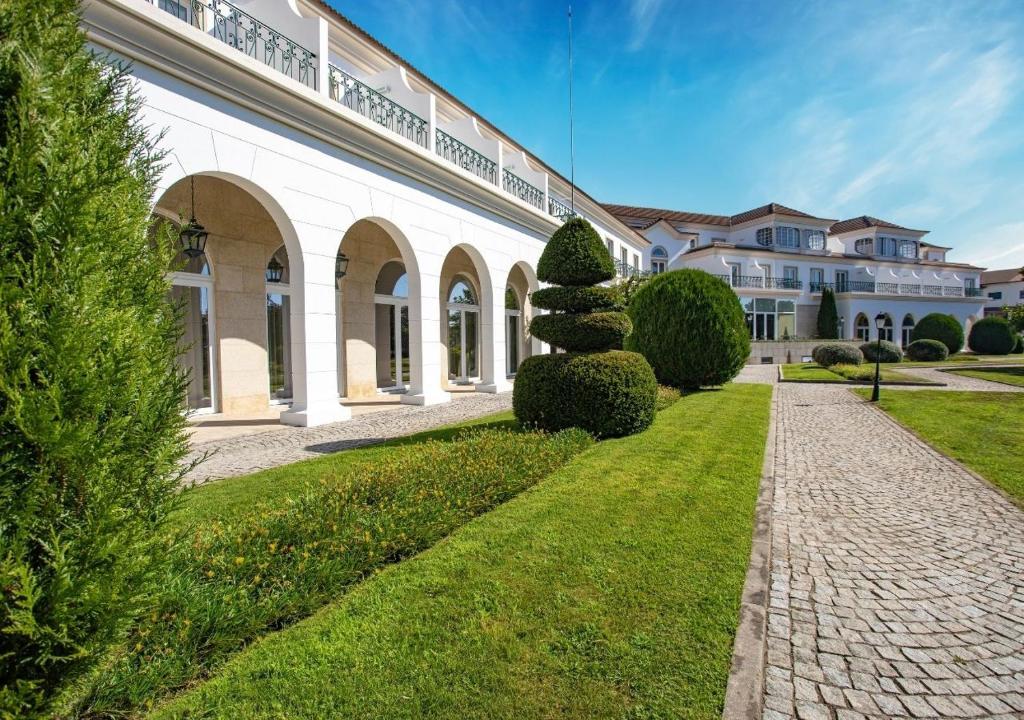 维塞乌Montebelo Principe Perfeito Viseu Garden Hotel的白色的大建筑,有小路和灌木丛