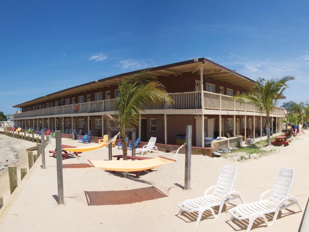 大洋城海洋汽车旅馆 的海滩上的一座建筑,配有椅子和冲浪板