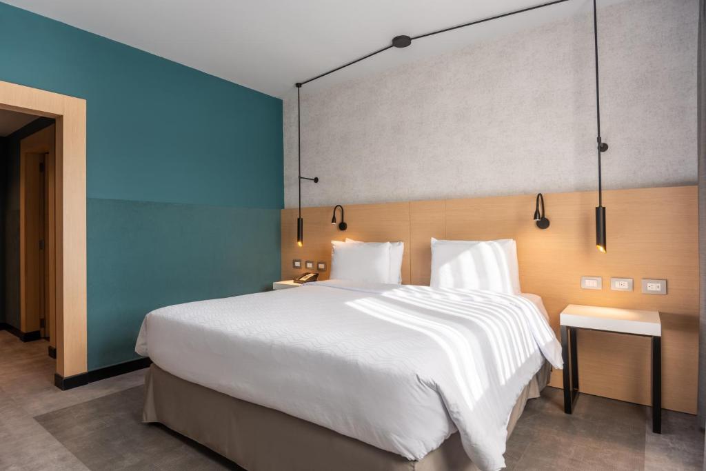 波哥大Novotel Bogota Parque 93的卧室配有一张白色大床和蓝色的墙壁