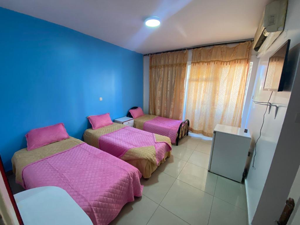 亚喀巴City Center Hostel的一间设有三张床和蓝色墙壁的房间