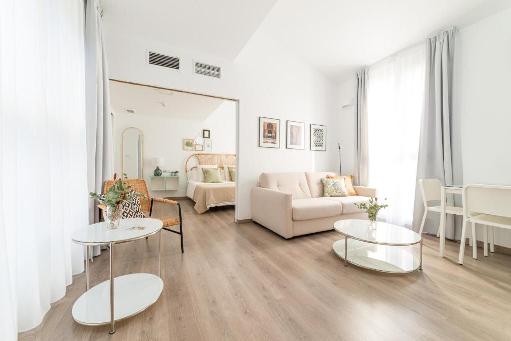 格拉纳达Apartamentos con encanto en el centro de Granada的客厅配有两张桌子和一张沙发
