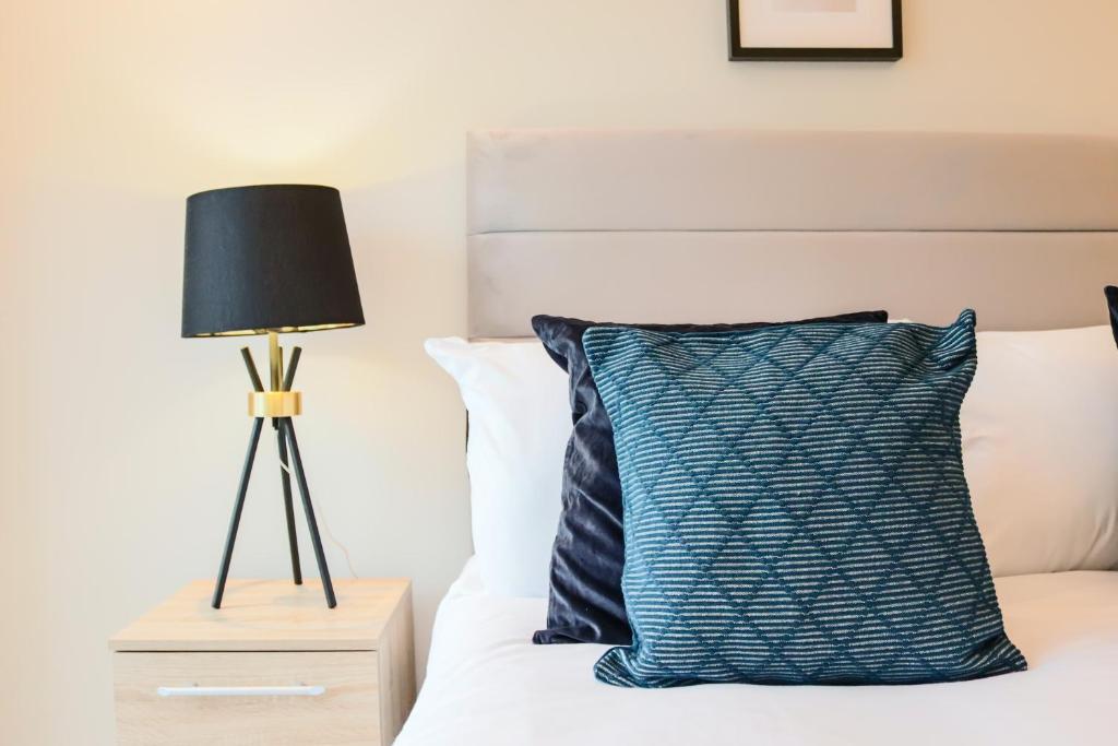 韦林花园城Portfolio Apartments - Welwyn Town Centre的一张带蓝色枕头和灯的床