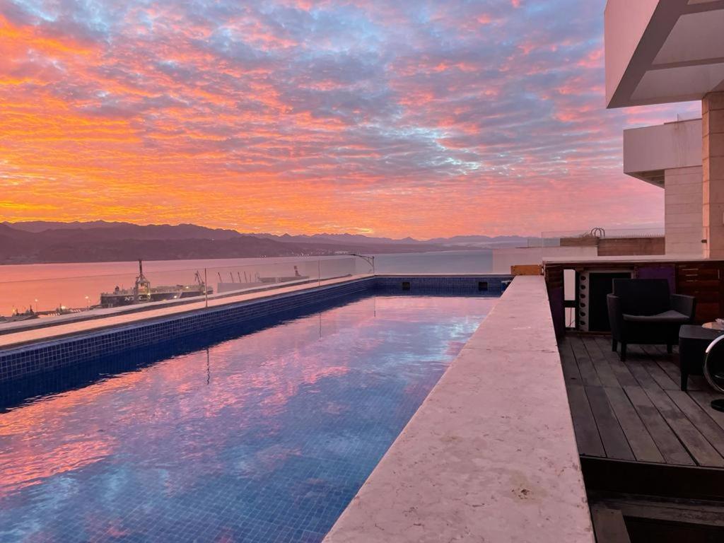 埃拉特Private pool Luxury penthouses sea view Eilat的一座享有日落美景的建筑屋顶上的游泳池