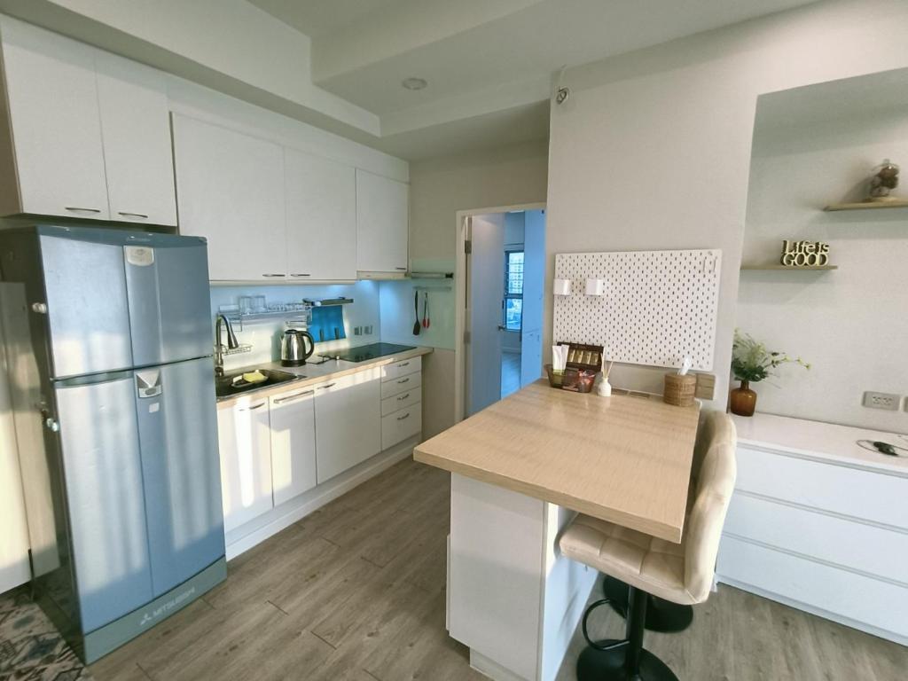 曼谷溫馨小屋的厨房配有白色橱柜和蓝色冰箱。
