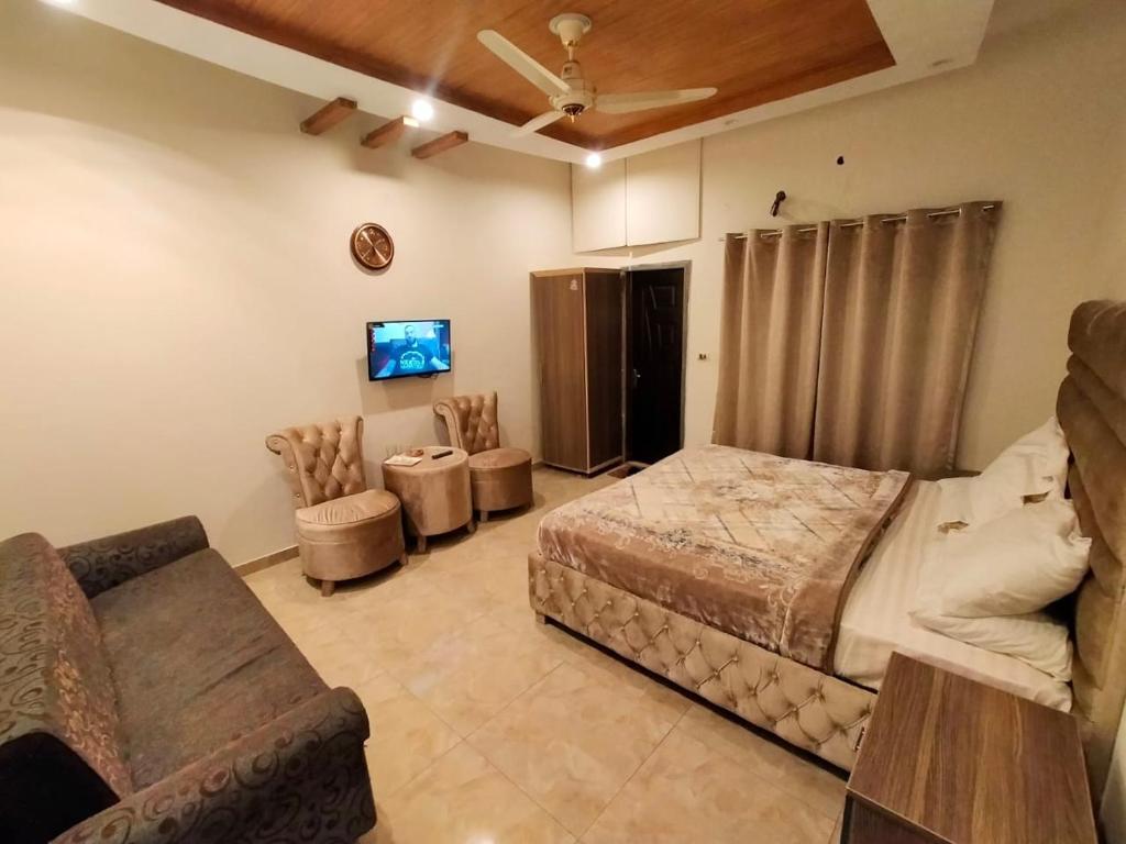 拉合尔Hotel Day In Emporium的一间卧室配有一张床、一张沙发和一台电视。