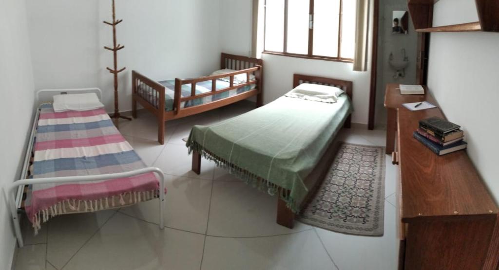 瓜拉廷格塔Casa residencial no centro de Guaratinguetá的一间卧室设有两张床、一张桌子和一个窗口