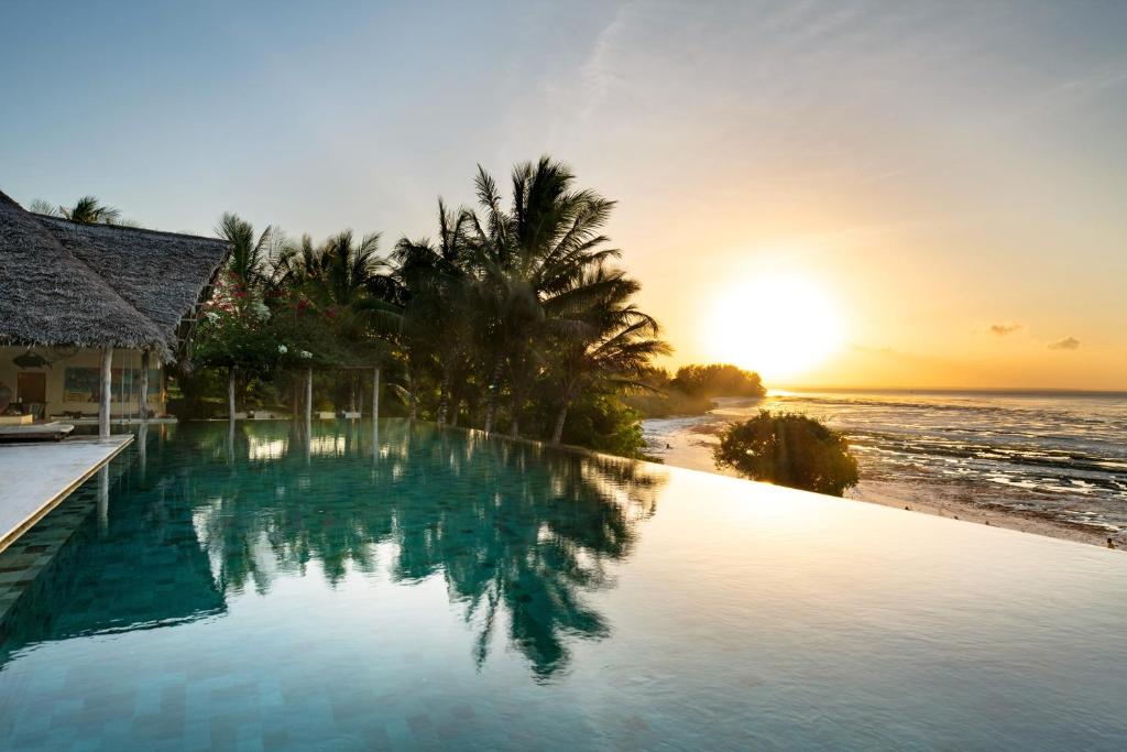 米查维Qambani Luxury Resort的海滩旁的游泳池,享有日落美景