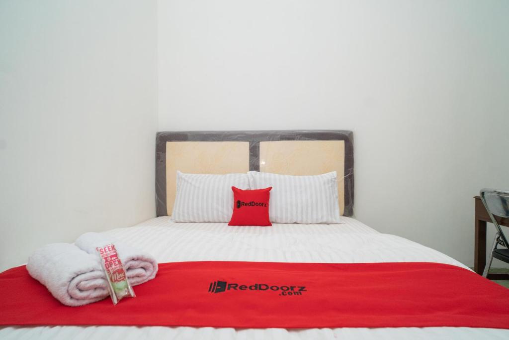 KumprungRedDoorz near Bundaran Ciceri的一张带红色毯子的床和两个枕头
