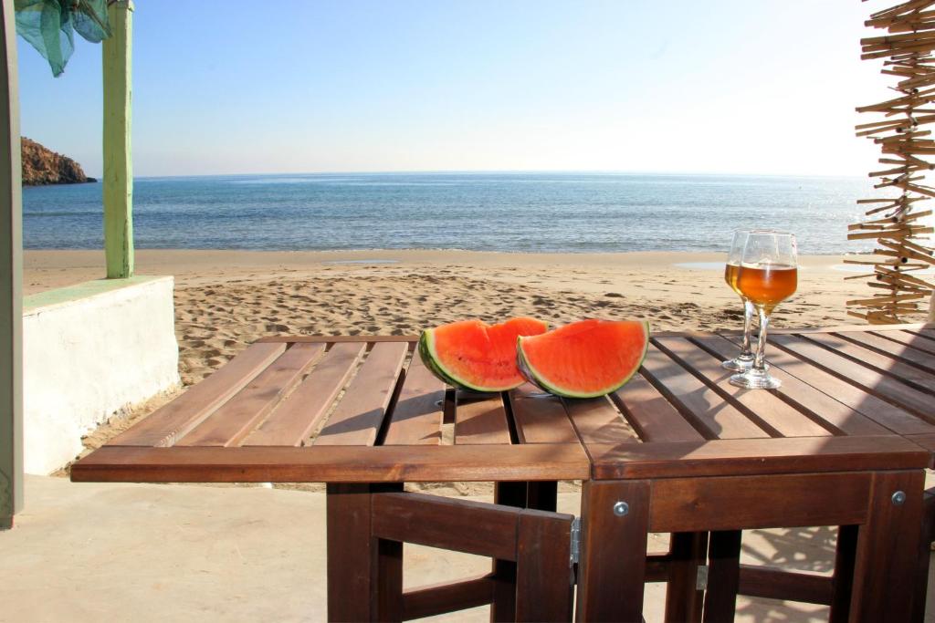 ProvatasManis Sirma (fisherman's house by the Sea)的一张木桌,上面有两片西瓜,放在沙滩上