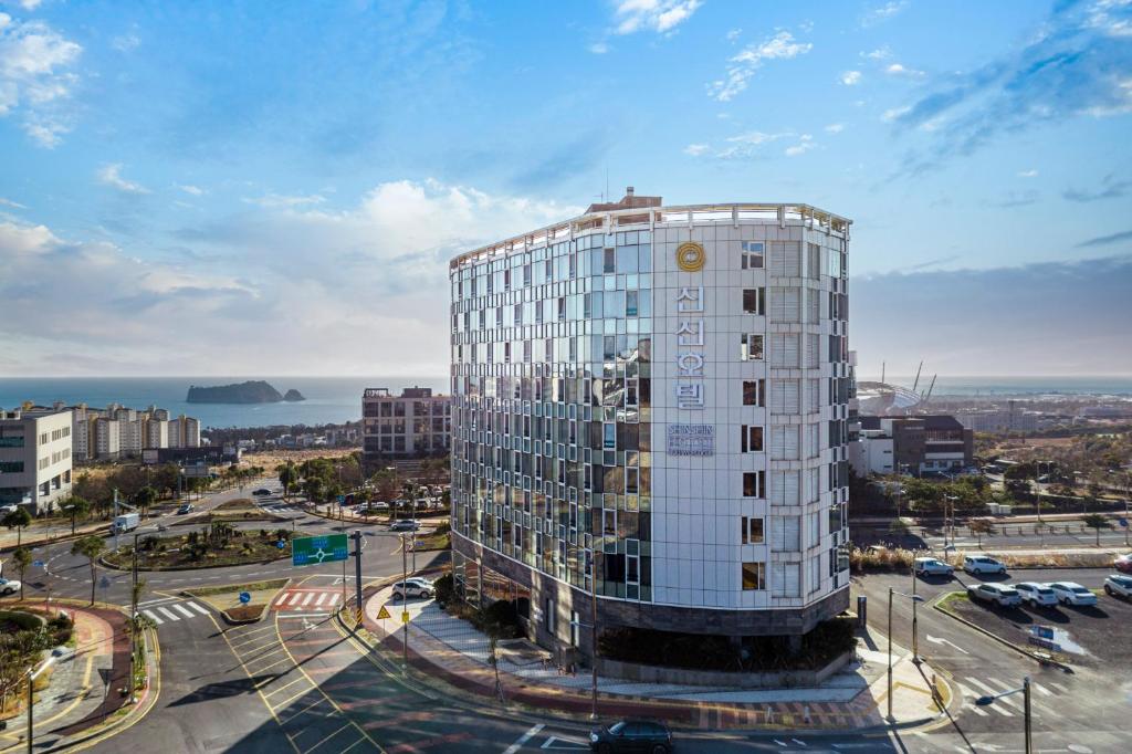 西归浦市Shin Shin Hotel Jeju Worldcup的城市前方高大的白色建筑