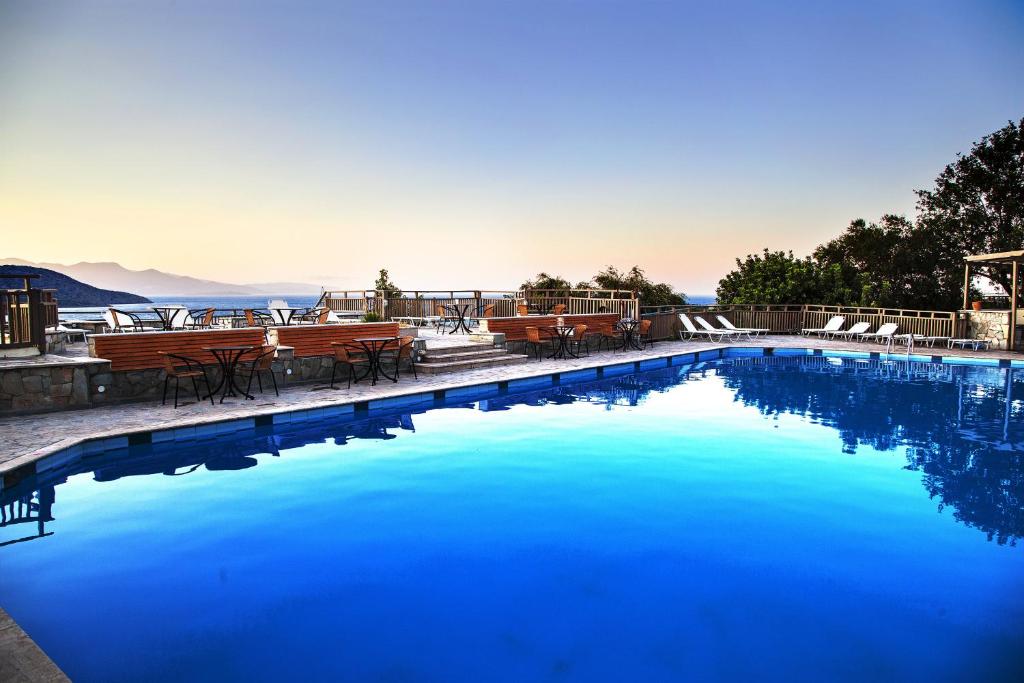伊斯特隆Elpida Village的一个带桌椅的大型蓝色游泳池