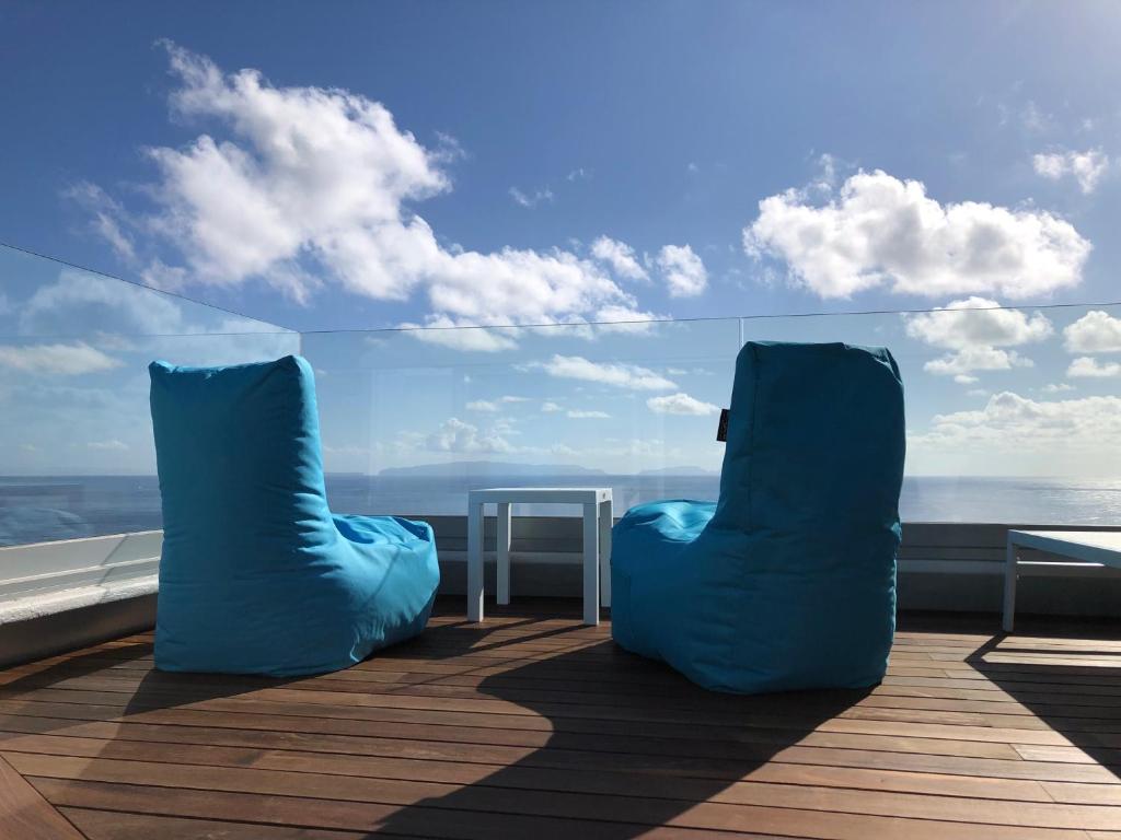 卡尼索Luxurious Penthouse Suite direct at sea的两把蓝色椅子坐在甲板上,眺望着大海