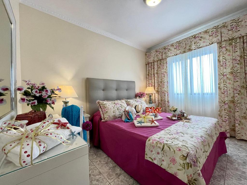 阿里纳加EmyCanarias Primera Línea De Playa的一间卧室配有一张带紫色床单的床和窗户。