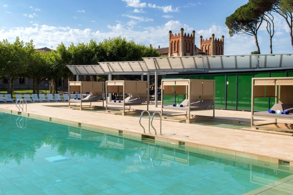 卡尔德斯德马拉维亚1881 Hotel Balneario Vichy Catalan的一个带椅子的游泳池和一个背景建筑