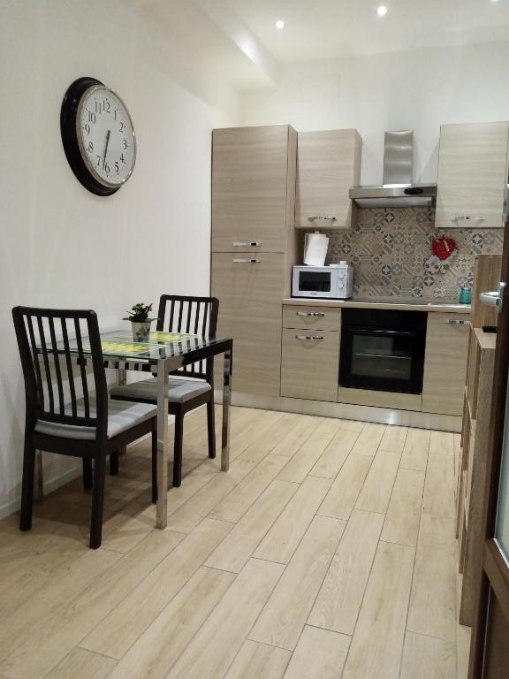 安科纳Appartamento Turistico "ortensia"的厨房配有桌椅和墙上的时钟