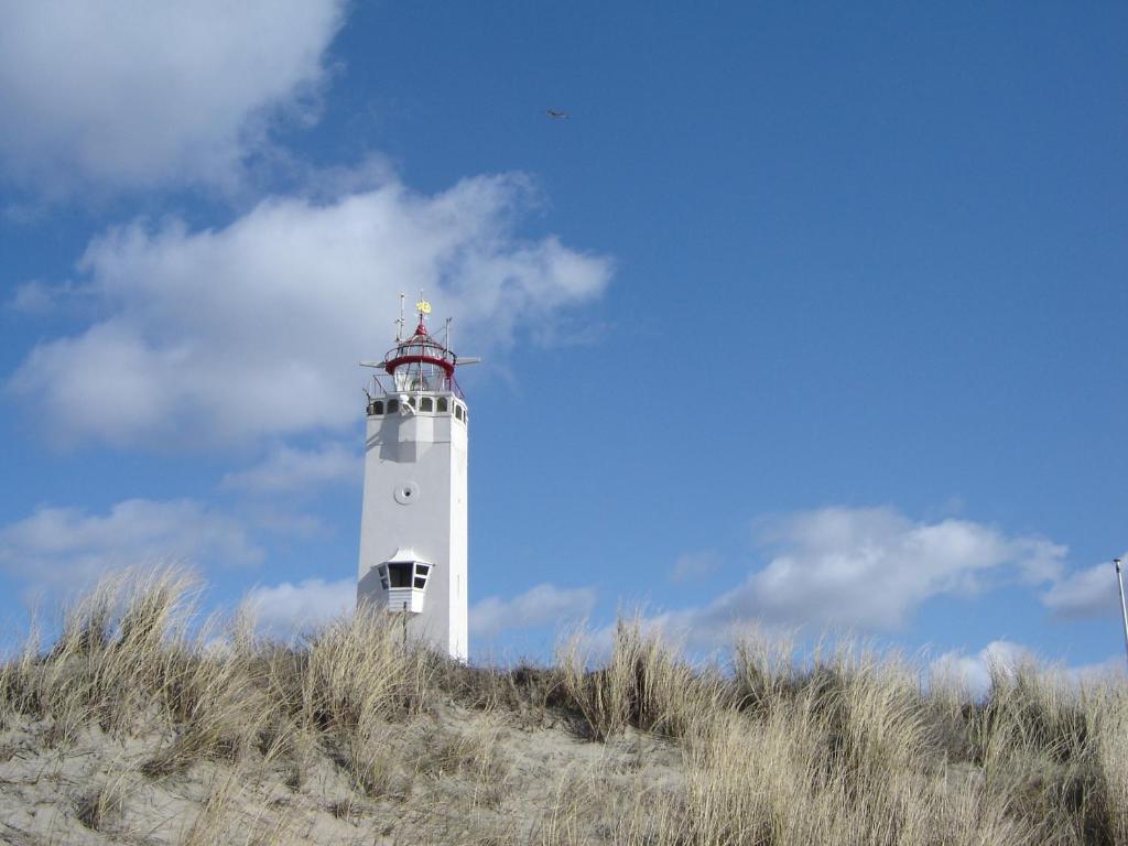 海滨诺德韦克Appartement "Zicht op de Vuurtoren"的山顶上的白色灯塔