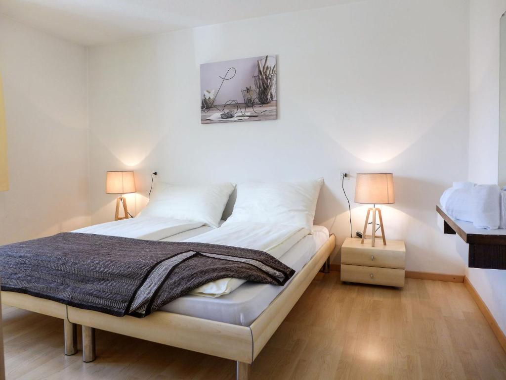 圣莫里茨圣莫里茨巴德奥瓦科茨奇纳二号公寓的一间卧室配有一张带白色墙壁的床和两盏灯。