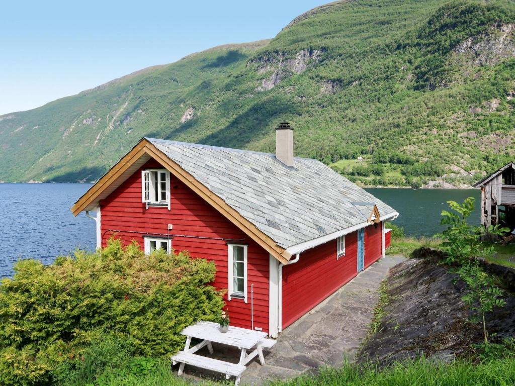 ArnefjordHoliday Home Johans Maria stova - FJS606 by Interhome的湖前有长凳的红色房子