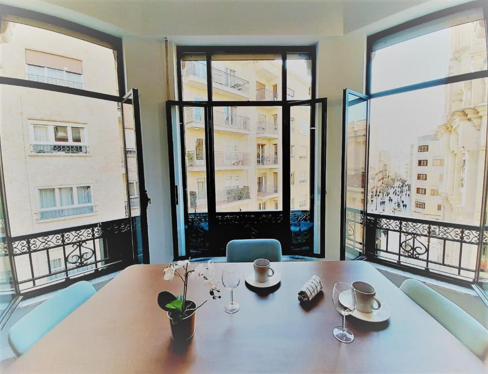 萨拉曼卡Apartamentos Vega by gaiarooms的一间带桌子和大窗户的用餐室
