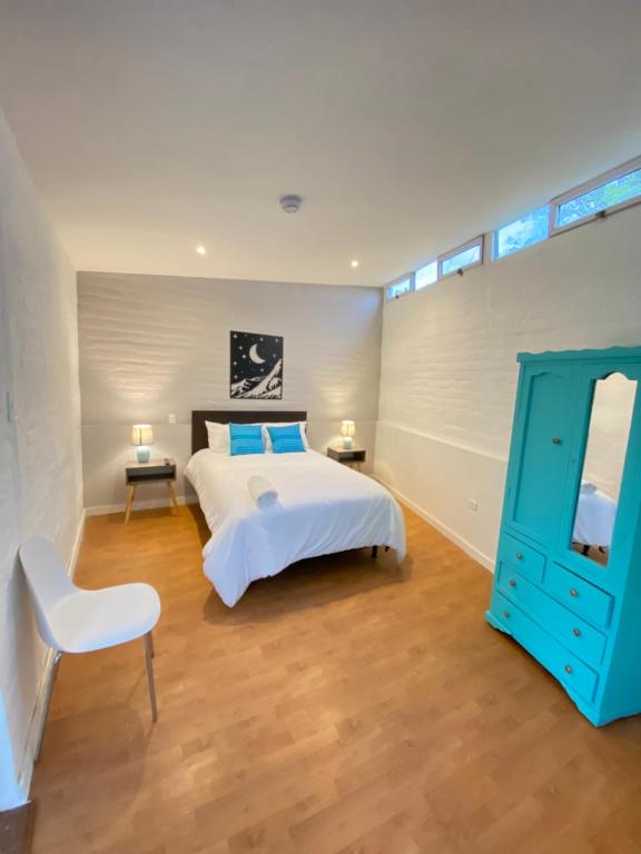 塔巴贝拉Springhills Quito Airport的卧室配有白色的床和蓝色橱柜
